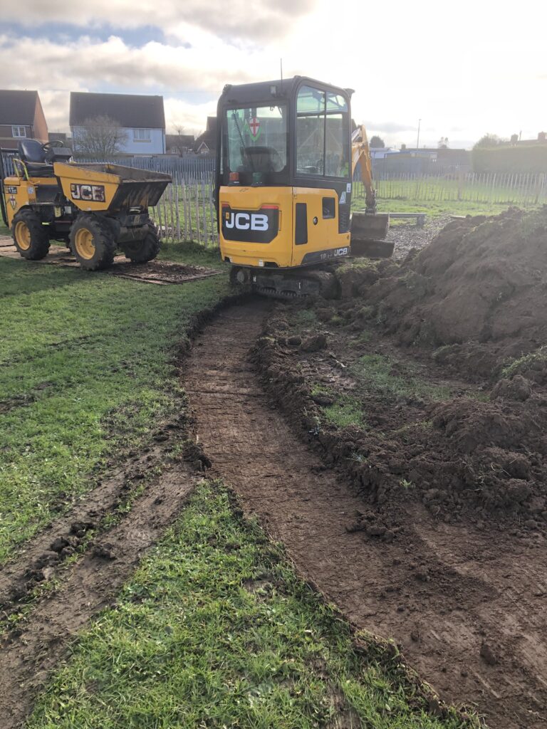 JCB digger with muddy path being dug